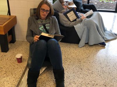 staff member reading with student in background